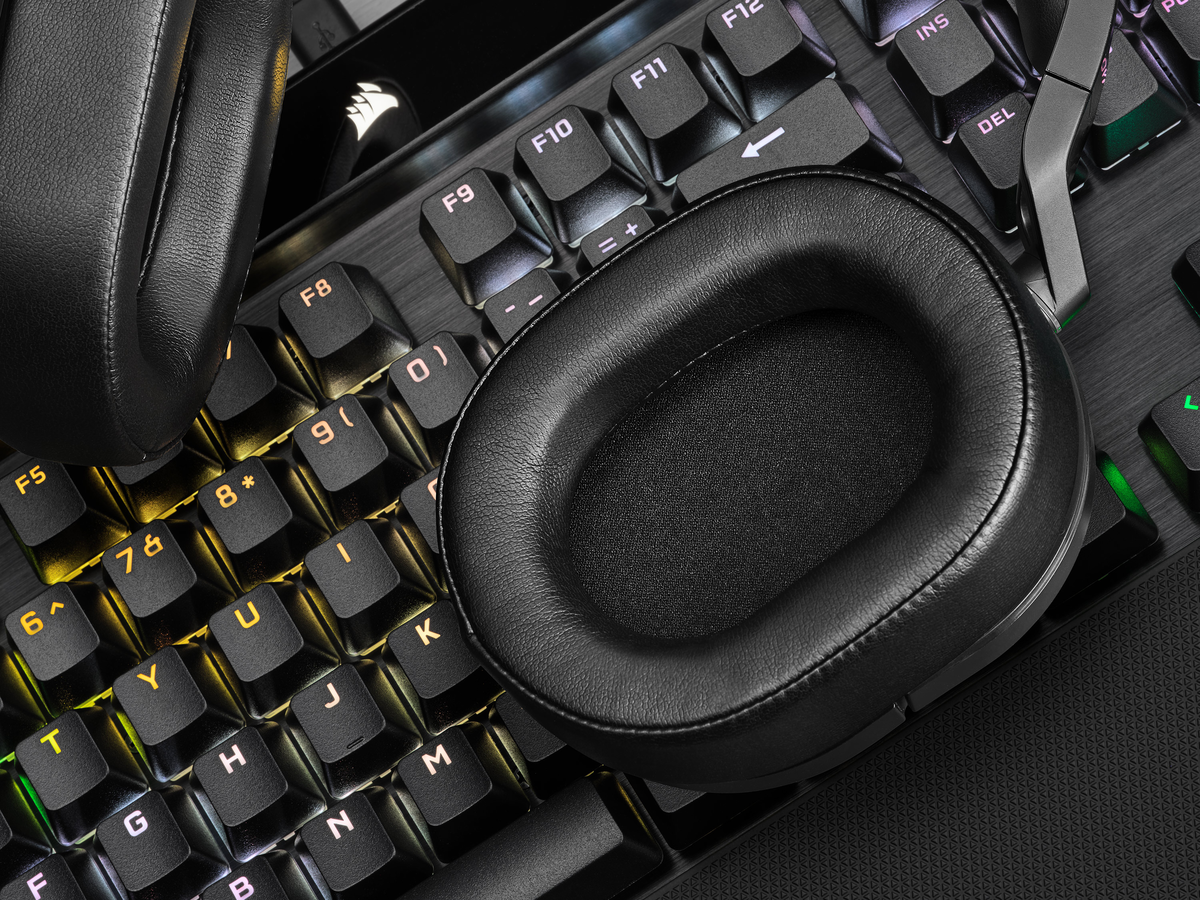 Un casque noir est posé sur un clavier noir. Le clavier a des lumières colorées.