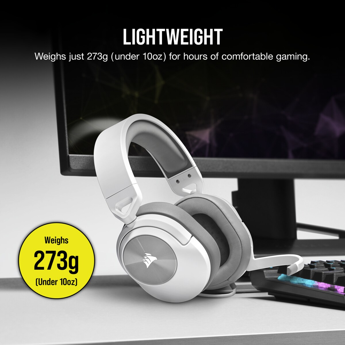 Weiße und graue Gaming-Kopfhörer auf einem Schreibtisch mit Monitor und Tastatur.