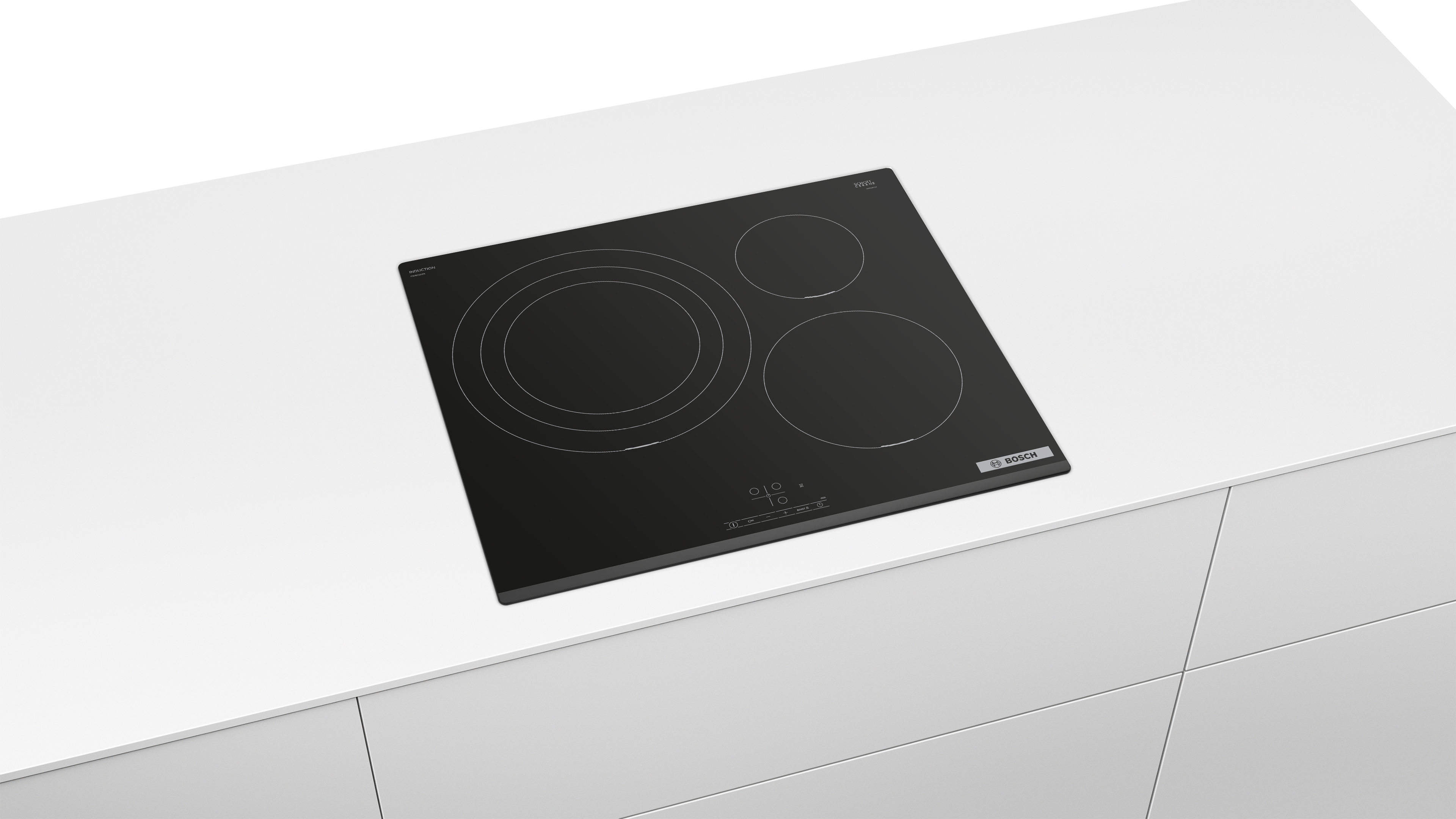 Una placa de inducción Bosch negra y cuadrada con tres quemadores circulares, sobre una encimera blanca.