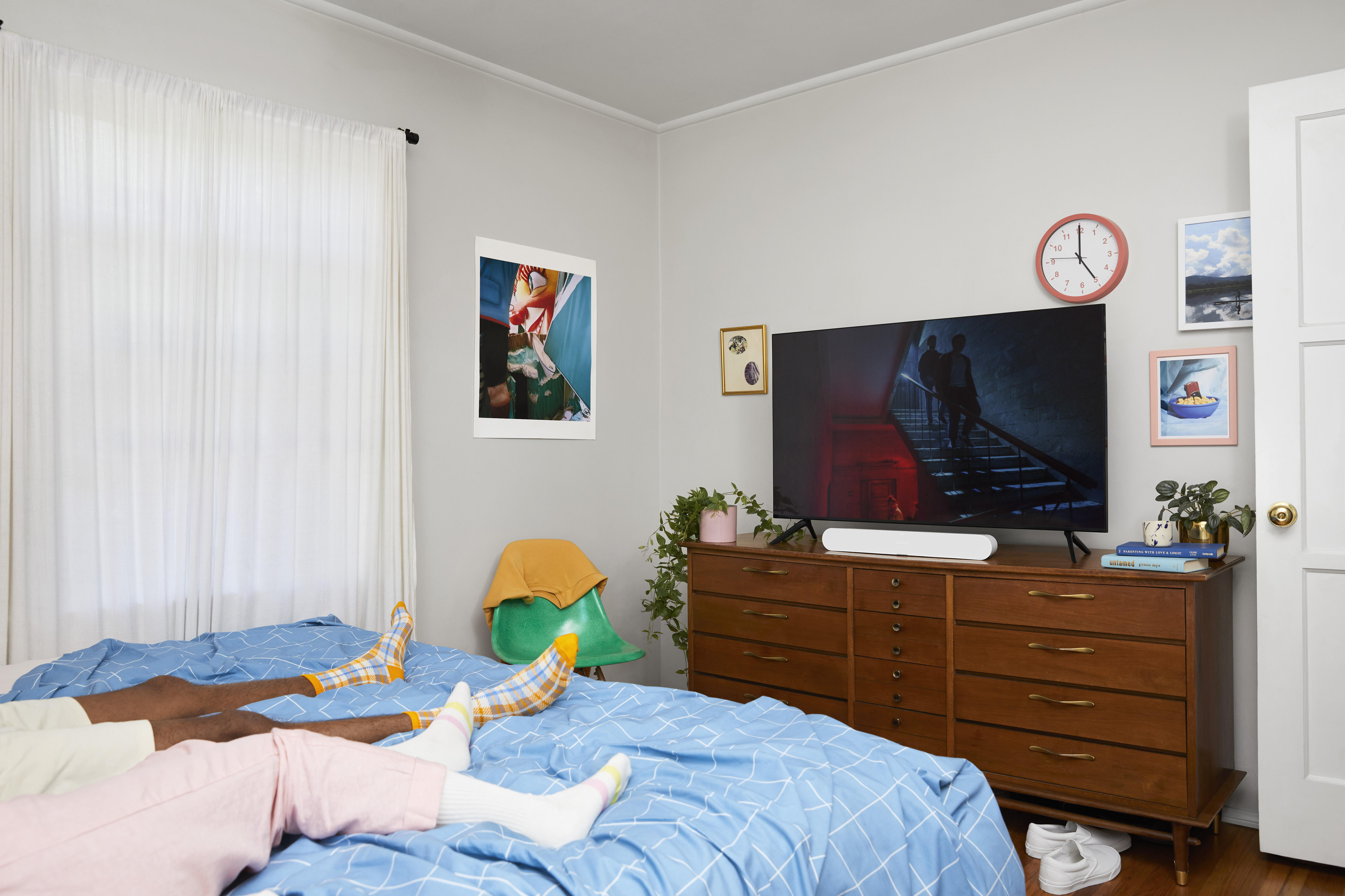 Schlafzimmer mit TV, Füßen auf Bett, Kunst und Dekoration.