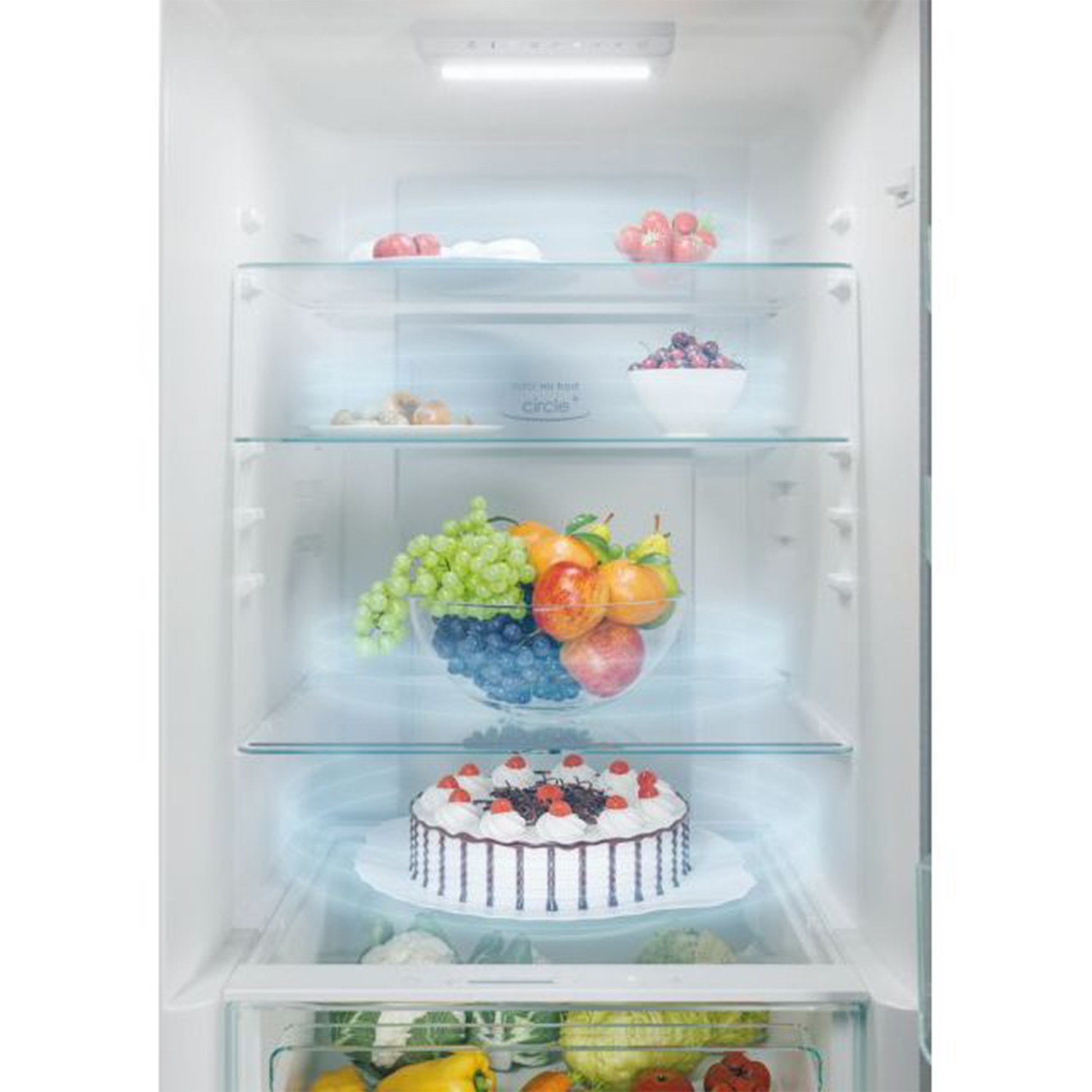 Frigorifero aperto con frutta, torta e altri alimenti su ripiani di vetro.