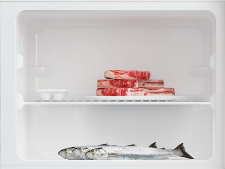 Refrigerador con carne en un estante. El estante inferior tiene pescado y huevos en el superior.