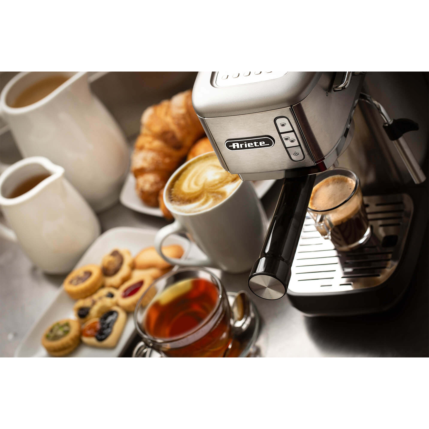 Macchina per espresso con caffè, pasticcini e tè. Sfondo bianco. Il caffè si sta facendo.