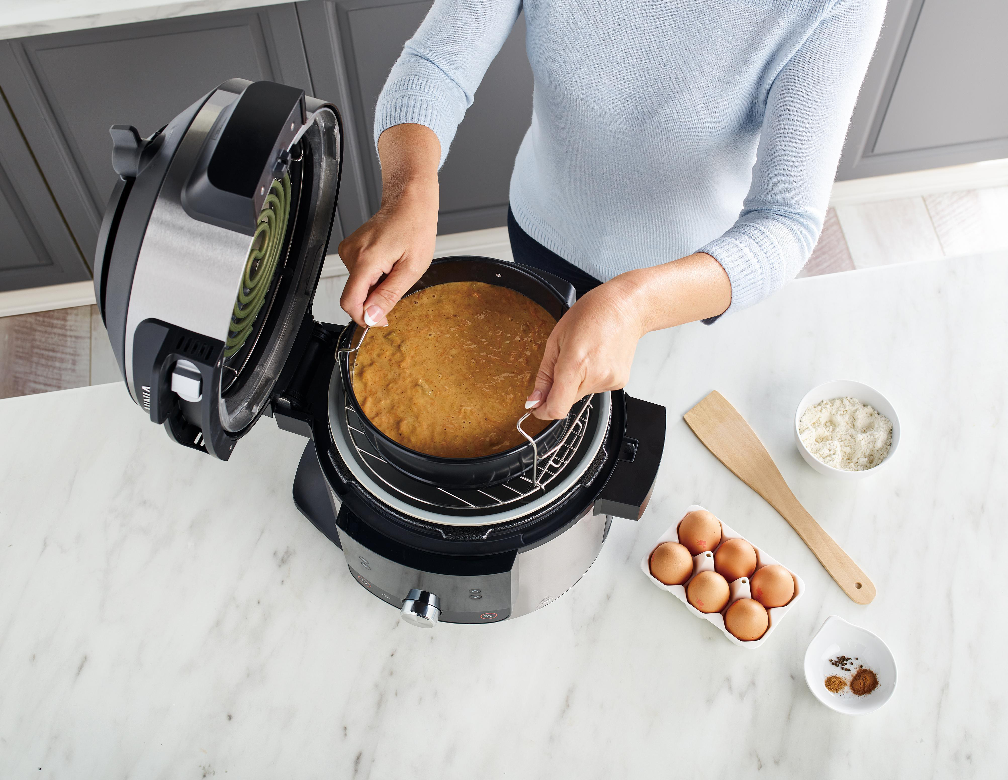 Frau, die einen Kuchen in ein Ninja Foodi-Gerät legt.