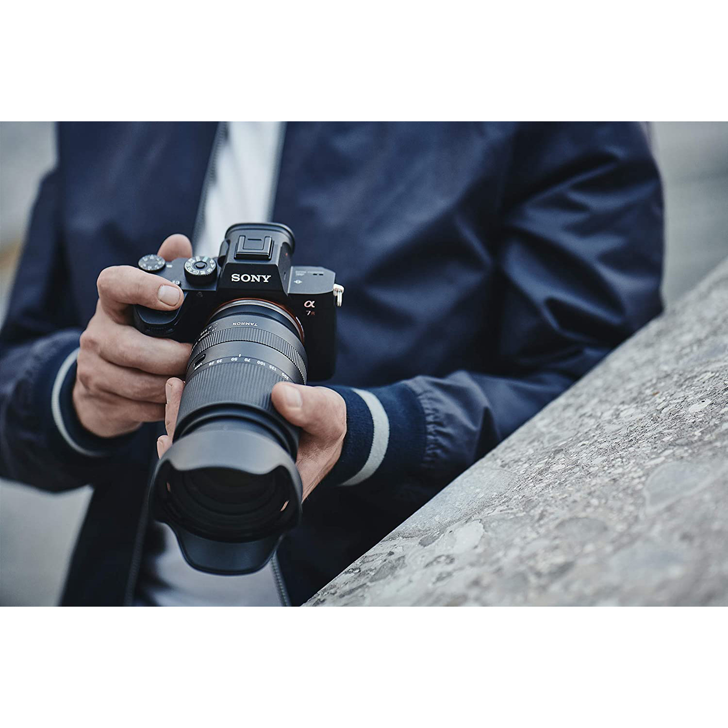Una persona che tiene in mano una fotocamera Sony nera con un obiettivo.