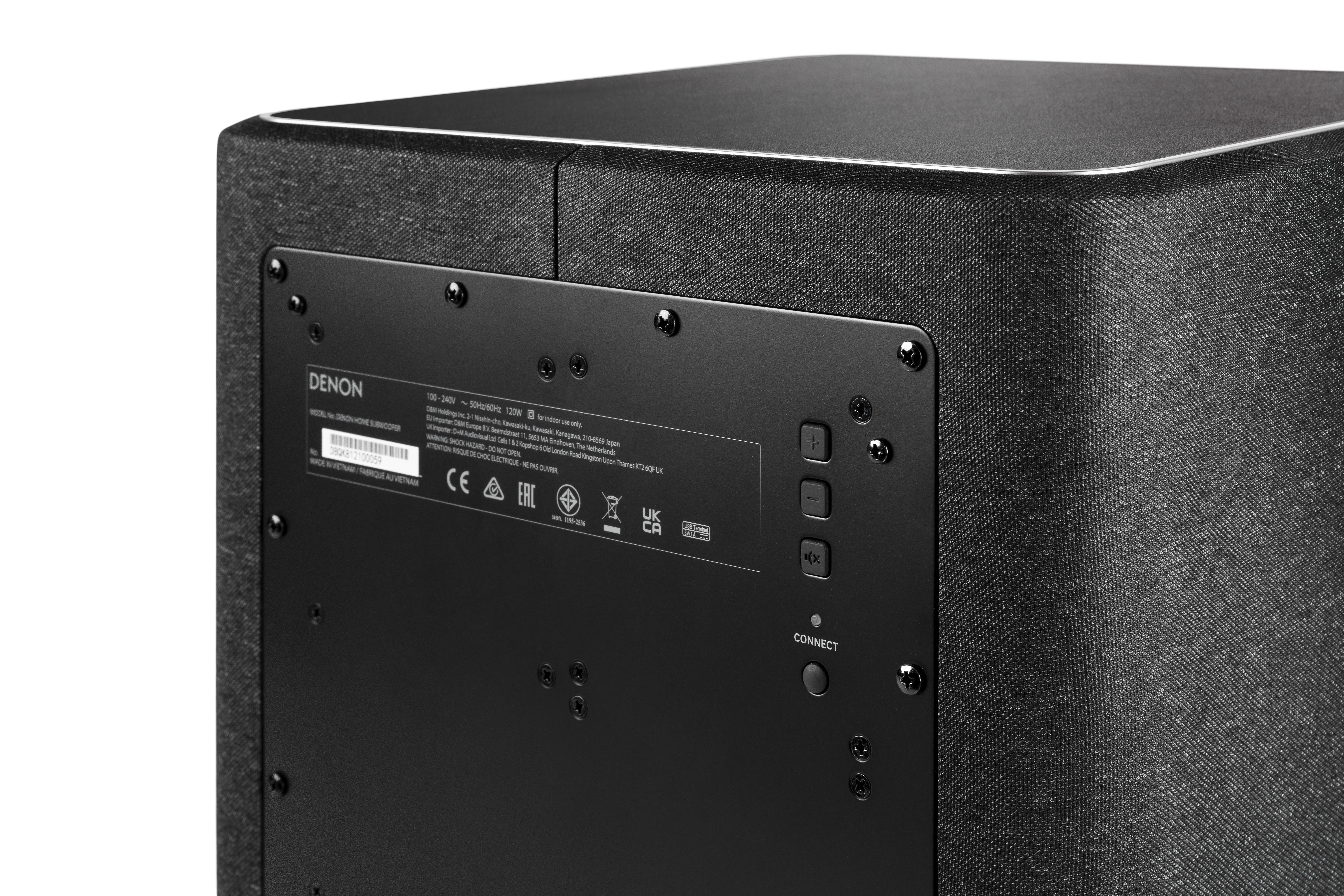 Die Rückseite eines Subwoofers mit Etikett, Anschlüssen und Knöpfen. Die Seite ist Stoff.