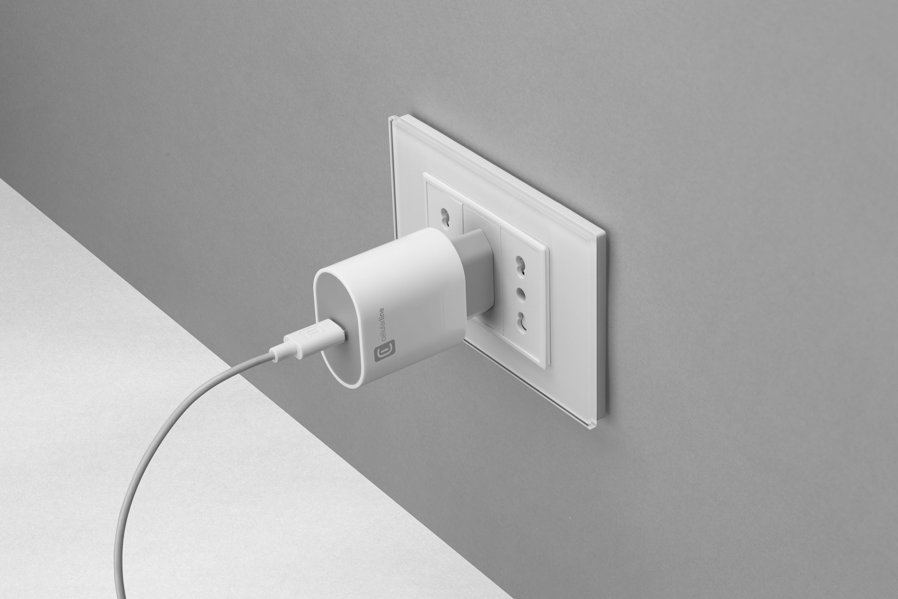 Weißes Ladegerät in einer Steckdose, mit angeschlossenem Kabel.