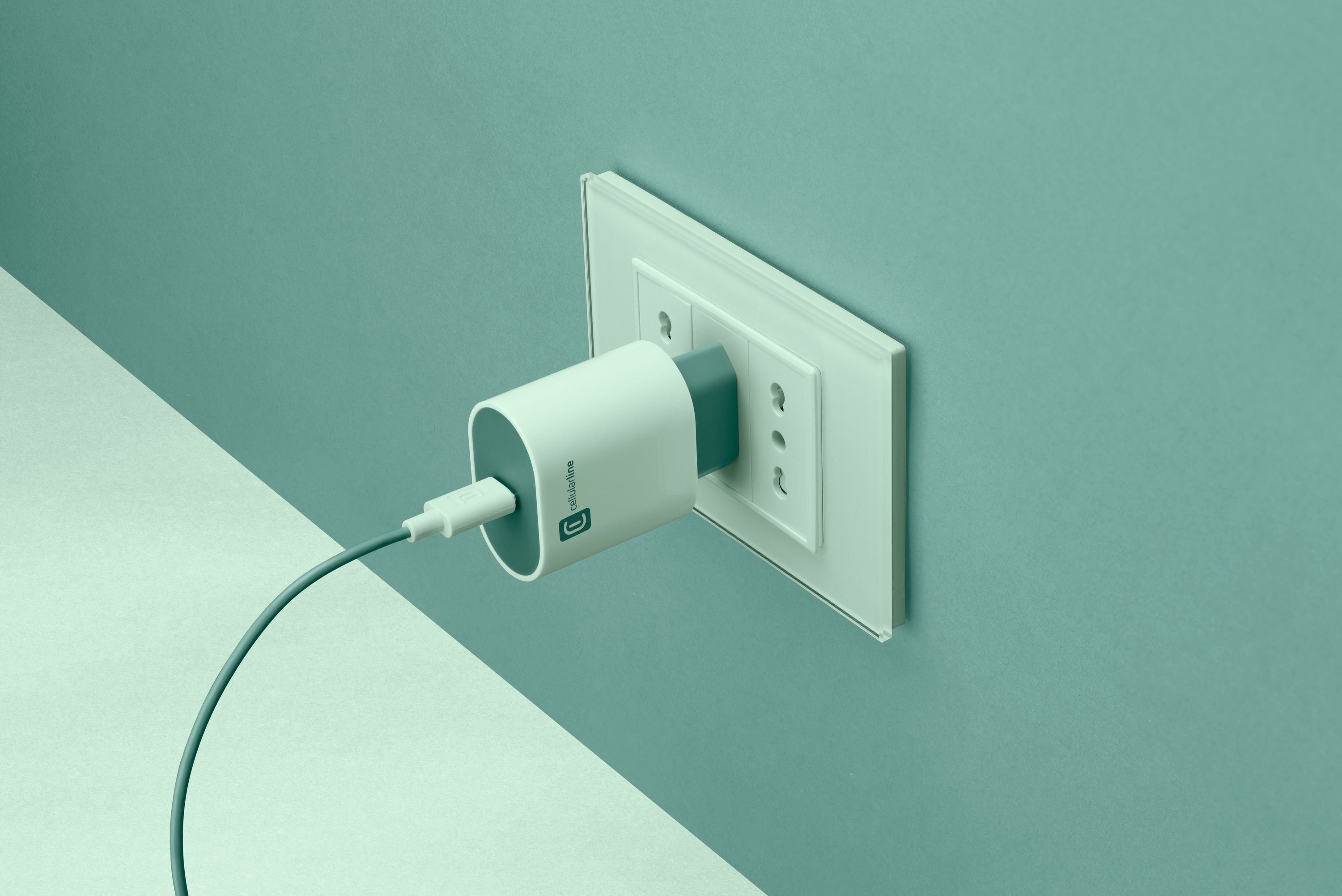 Un caricabatterie elettrico collegato a una presa a muro. Il caricabatterie è bianco e grigio.