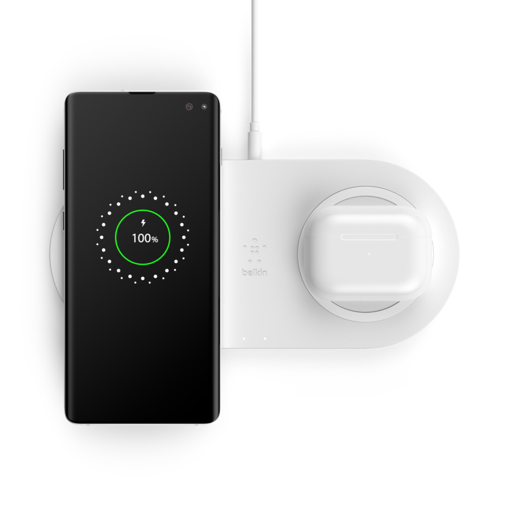 Beyaz bir şarj pad'inde kablosuz olarak şarj olan bir telefon, yanında bir çift beyaz kablosuz kulaklıkla.