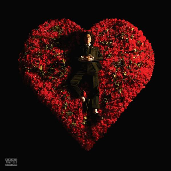 Mann im Anzug liegt auf einem Herz aus roten Rosen.