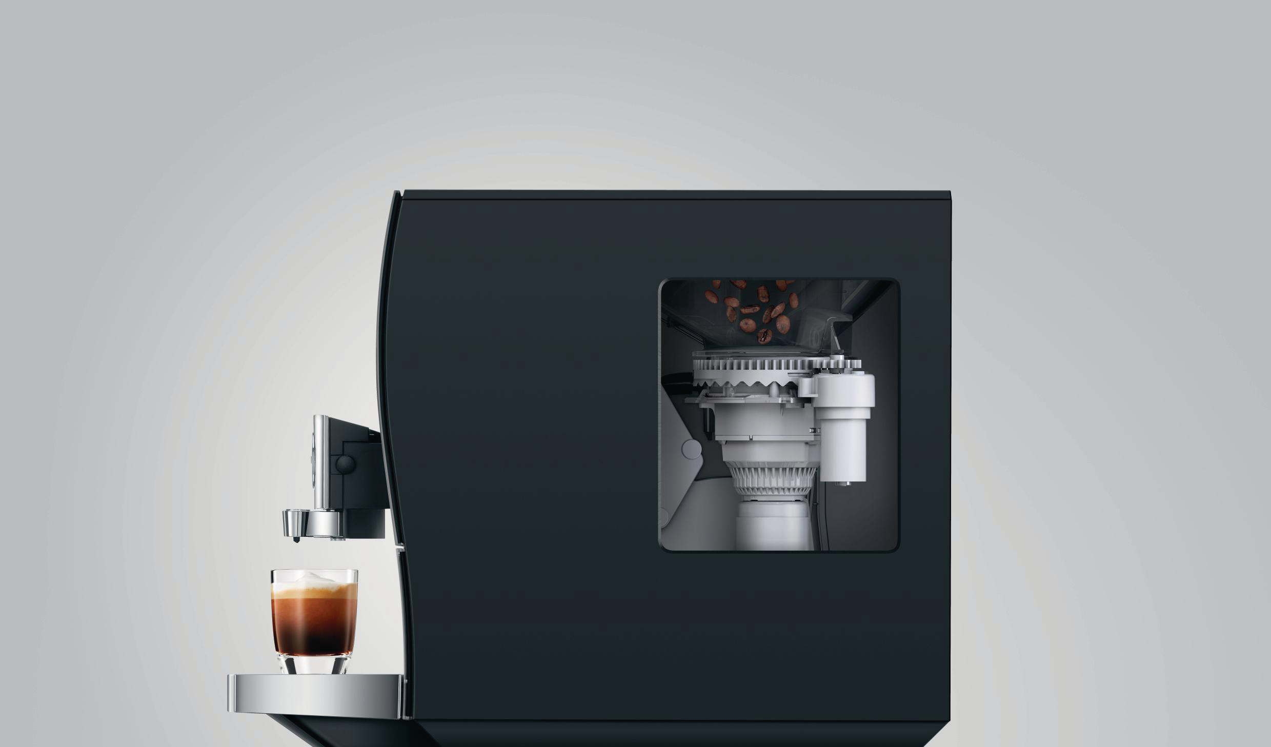 Eine schwarze Kaffeemaschine mit sichtbaren internen Komponenten und einem Glas Espresso. Weißer Hintergrund.