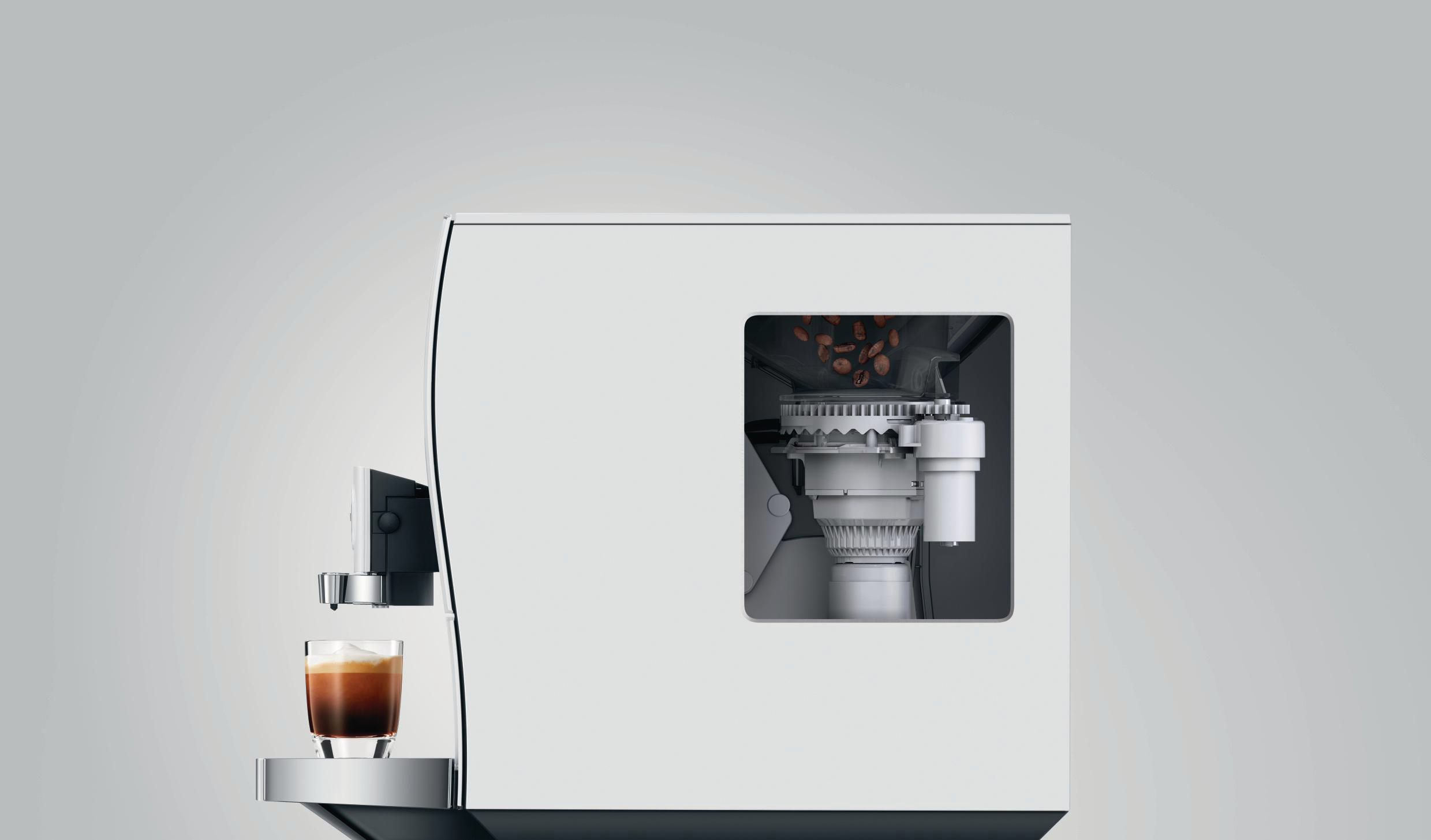 Weiße Jura-Kaffeemaschine mit sichtbaren Bohnen und eine Glastasse mit Kaffee auf dem Ständer.