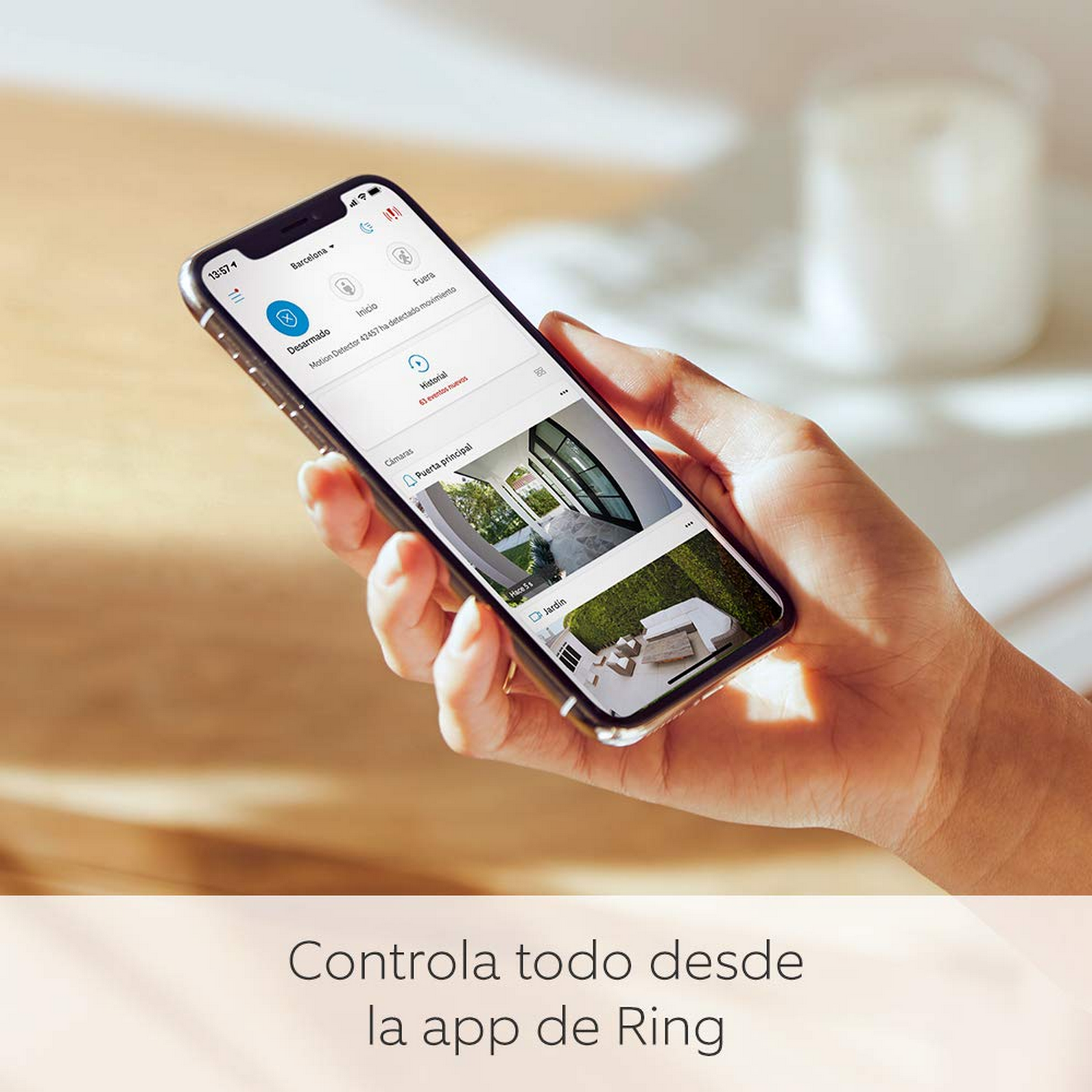 Mano sosteniendo un teléfono, interfaz de la aplicación visible, casa, texto abajo.