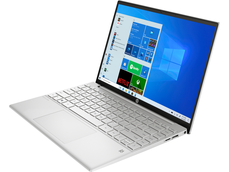 Un portátil blanco, abierto, sobre una superficie blanca, mostrando un escritorio de Windows con varias apps.