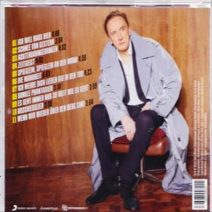 Mann in einem leichten Mantel sitzt auf einem Stuhl. Im Hintergrund eine Holzvertäfelung und Album-Trackliste.