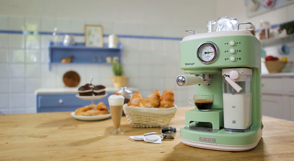 Egy mentazöld vintage kávéfőző. A táblán croissant, kávé és sütemény van.