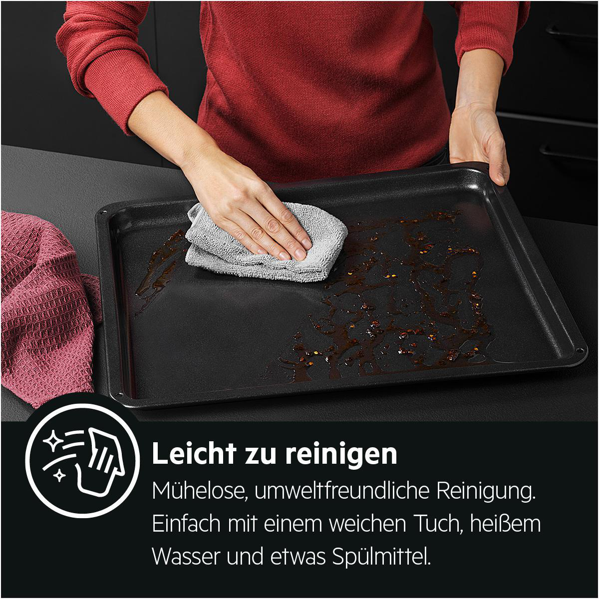 Hand wischt schwarzes Backblech mit grauem Tuch ab. Text: Leicht zu reinigen.