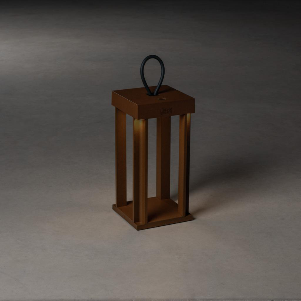 Eine quadratische Holzlaterne mit vertikalen Lamellen, einem schwarzen Griff und warmem Licht im Inneren.
