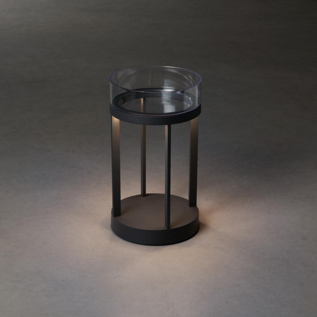 Eine zylindrische Außenlampe mit klarem Glasaufsatz und dunkler Basis.