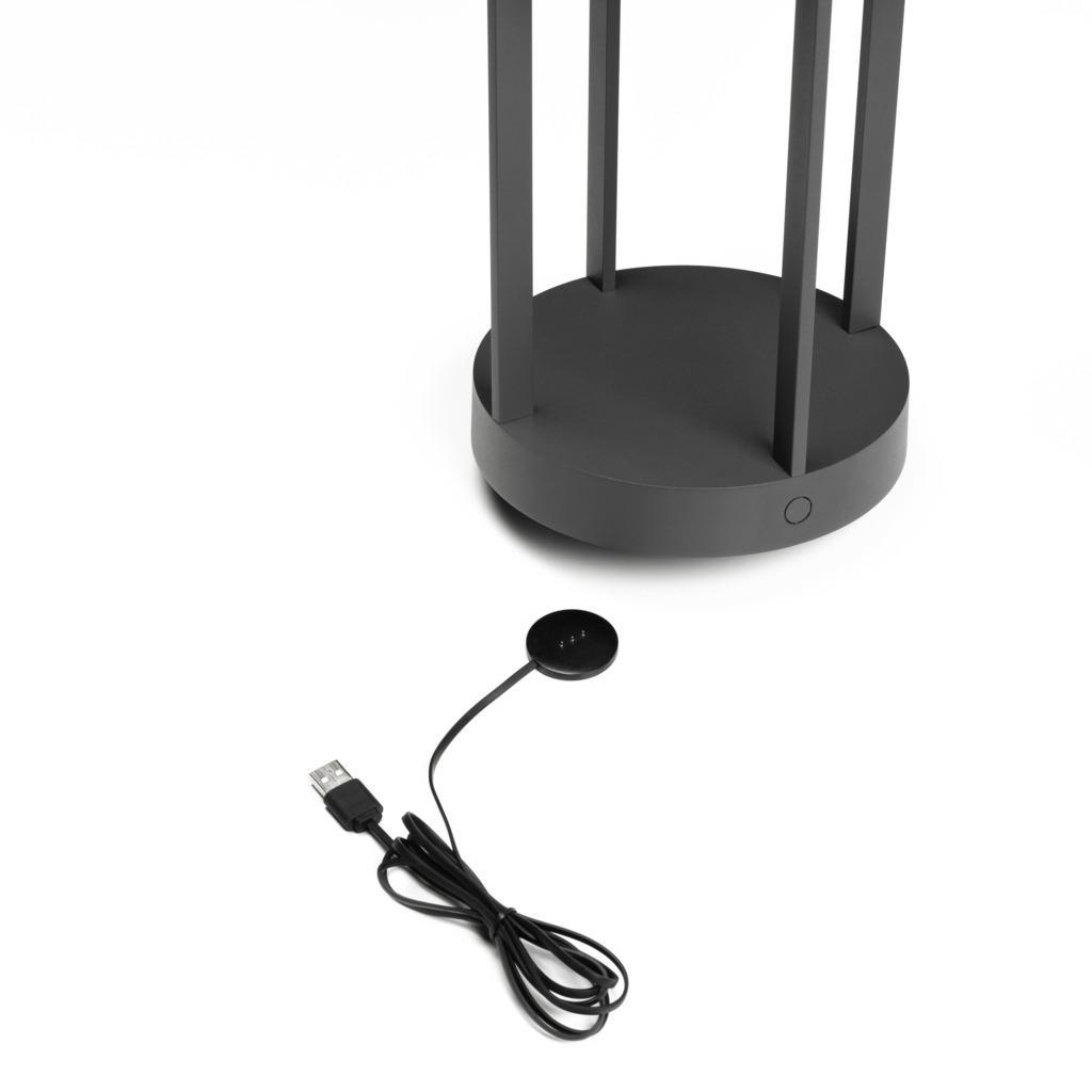 Ein schwarzer Lampensockel mit USB-Kabel und Ladepad. Weißer Hintergrund.