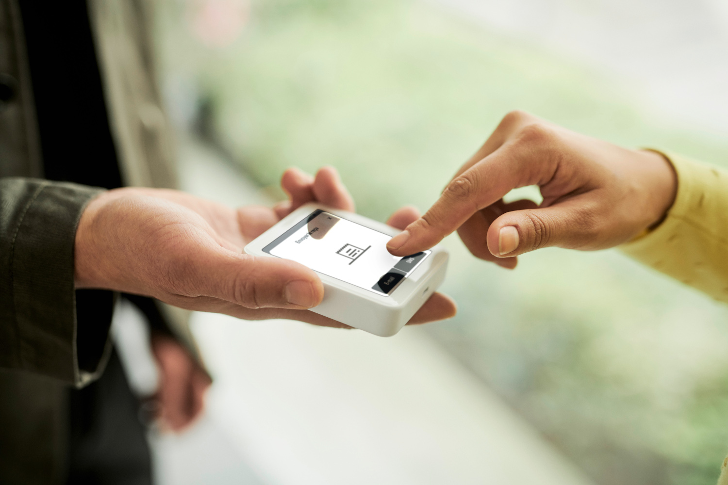 Deux mains interagissent avec un terminal de paiement blanc, montrant un bouton.