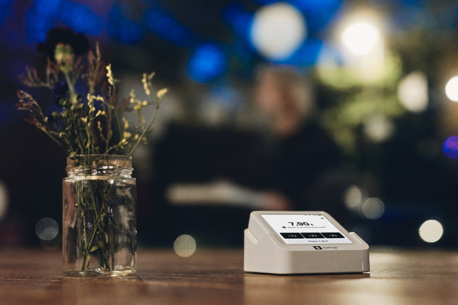 Un chargeur blanc avec un affichage numérique et un vase de fleurs sur une table.