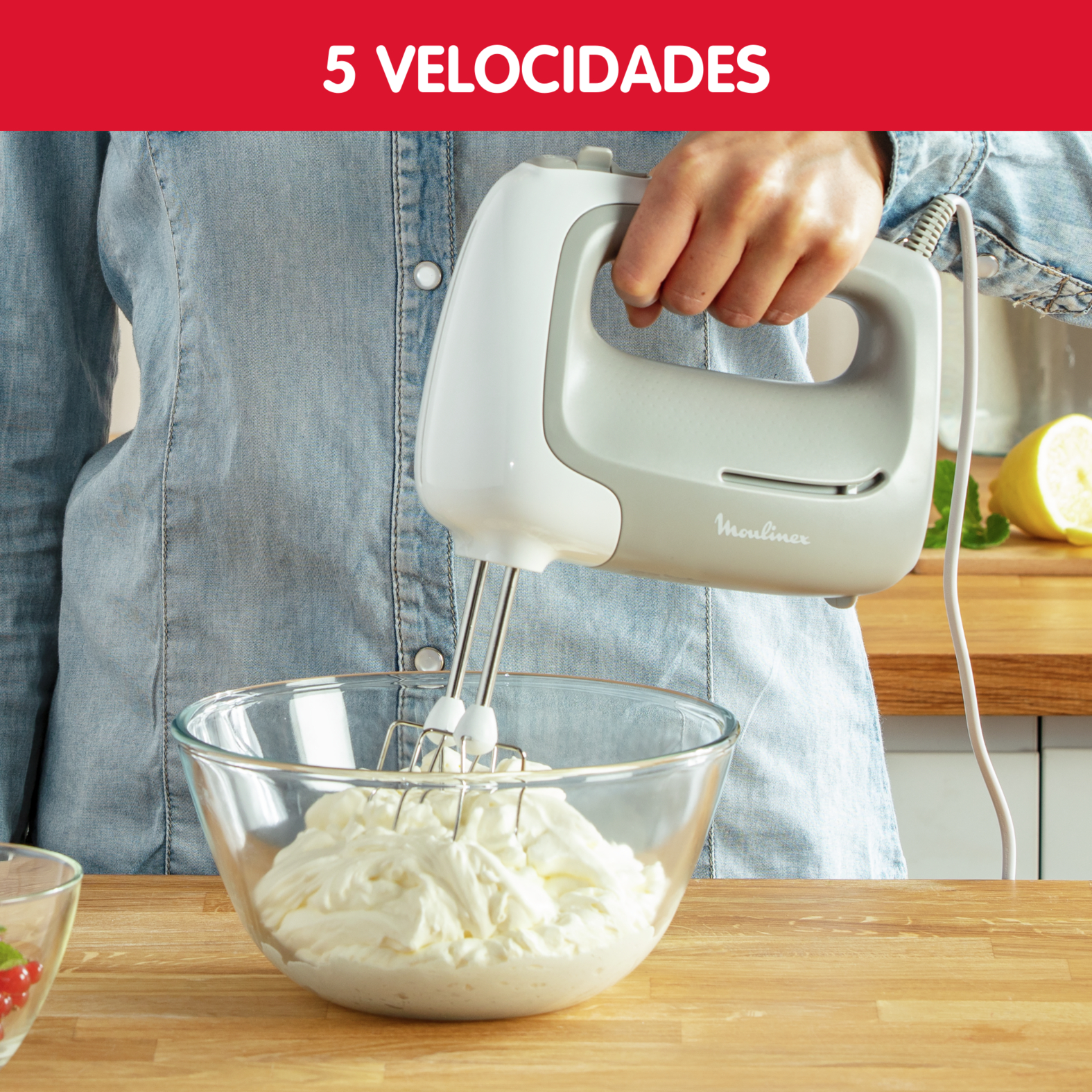 Una persona usa una batidora de mano Moulinex, mezclando crema en un bol de vidrio.