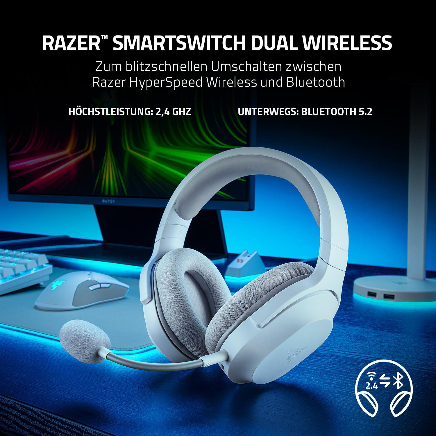 Weiße Razer-Kopfhörer mit Mikrofon auf einem blauen Schreibtisch. Auch eine Maus und ein Monitor.