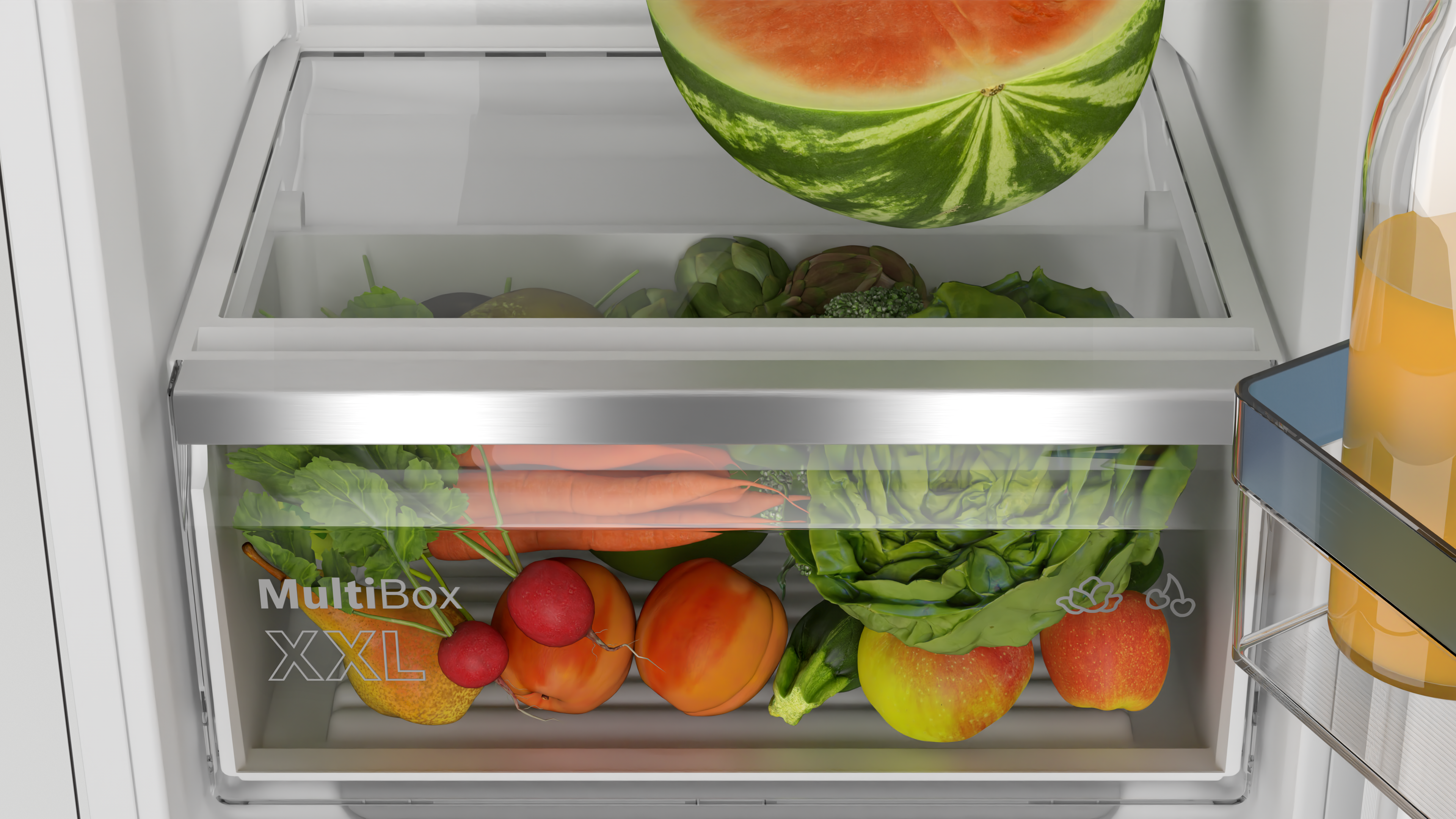 Refrigerator drawer with fresh vegetables: lettuce, carrots, apples, and watermelon.