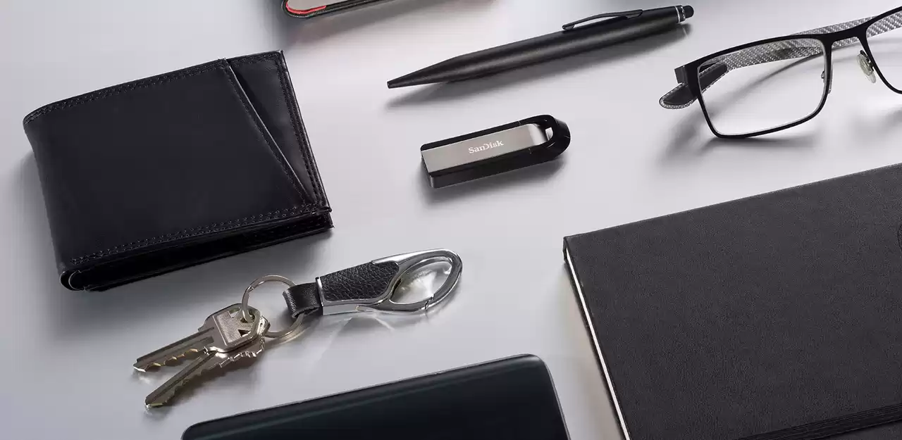 Irodai kiegészítők gyűjteménye: pénztárca, toll, USB meghajtó, szemüveg, jegyzetfüzet és kulcsok.