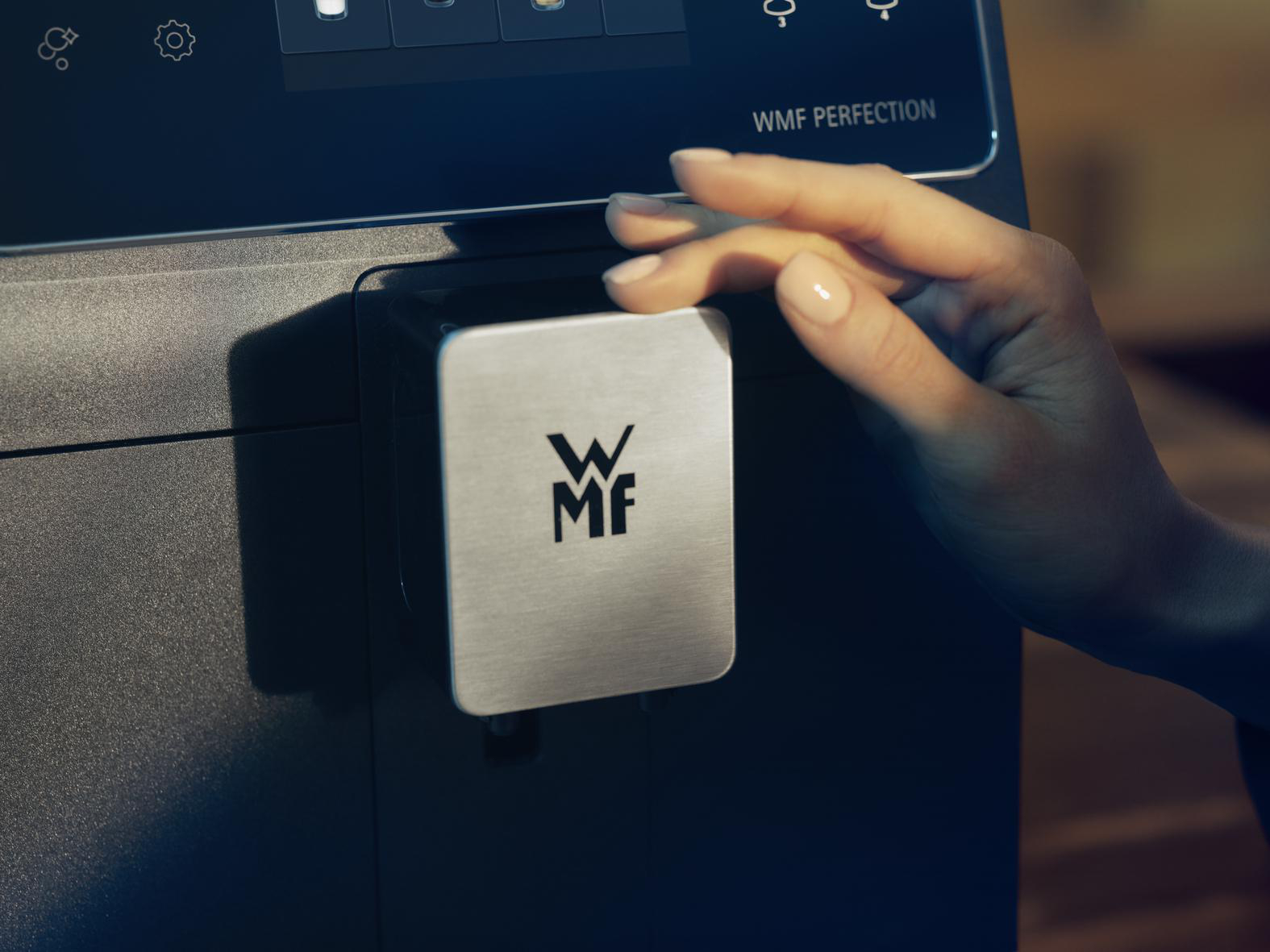Hand setzt Edelstahldeckel auf Kaffeemaschine.