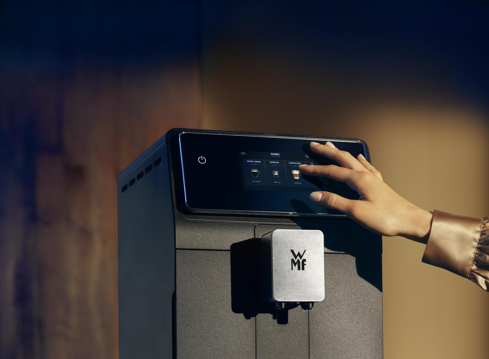 Eine Hand berührt den Bildschirm einer Kaffeemaschine. Die Maschine ist schwarz, mit verschiedenen Knöpfen.