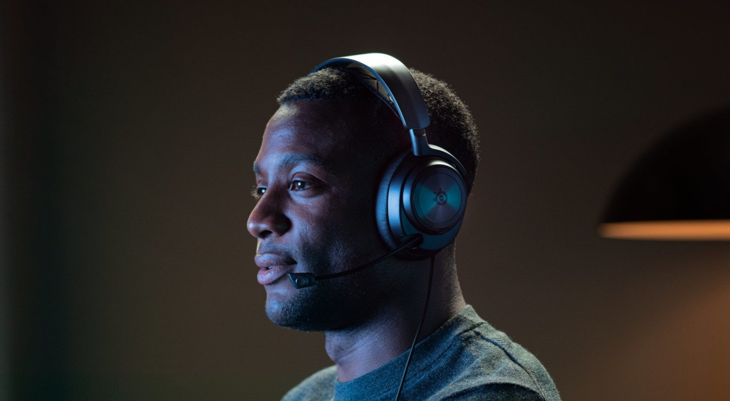 A man wearing black headphones with a microphone is looking to the left.
