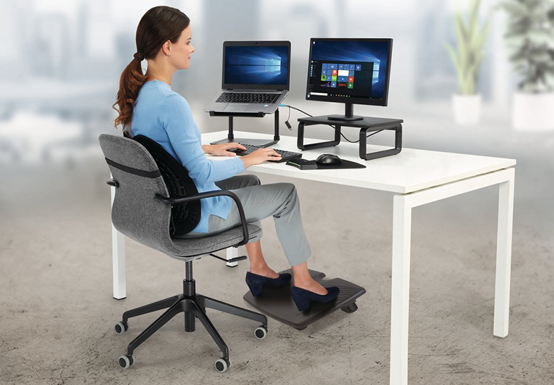 Egy nő laptopon és monitoron dolgozik egy asztalnál.