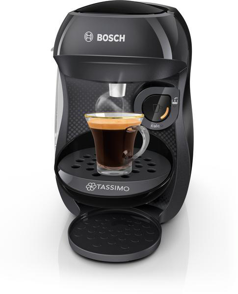 Eine schwarze Bosch Tassimo Kaffeemaschine mit einer Glastasse Kaffee im Vordergrund.