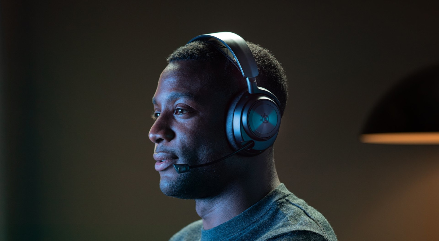 Man with headset, listening. Dark background with a monitor glow.
