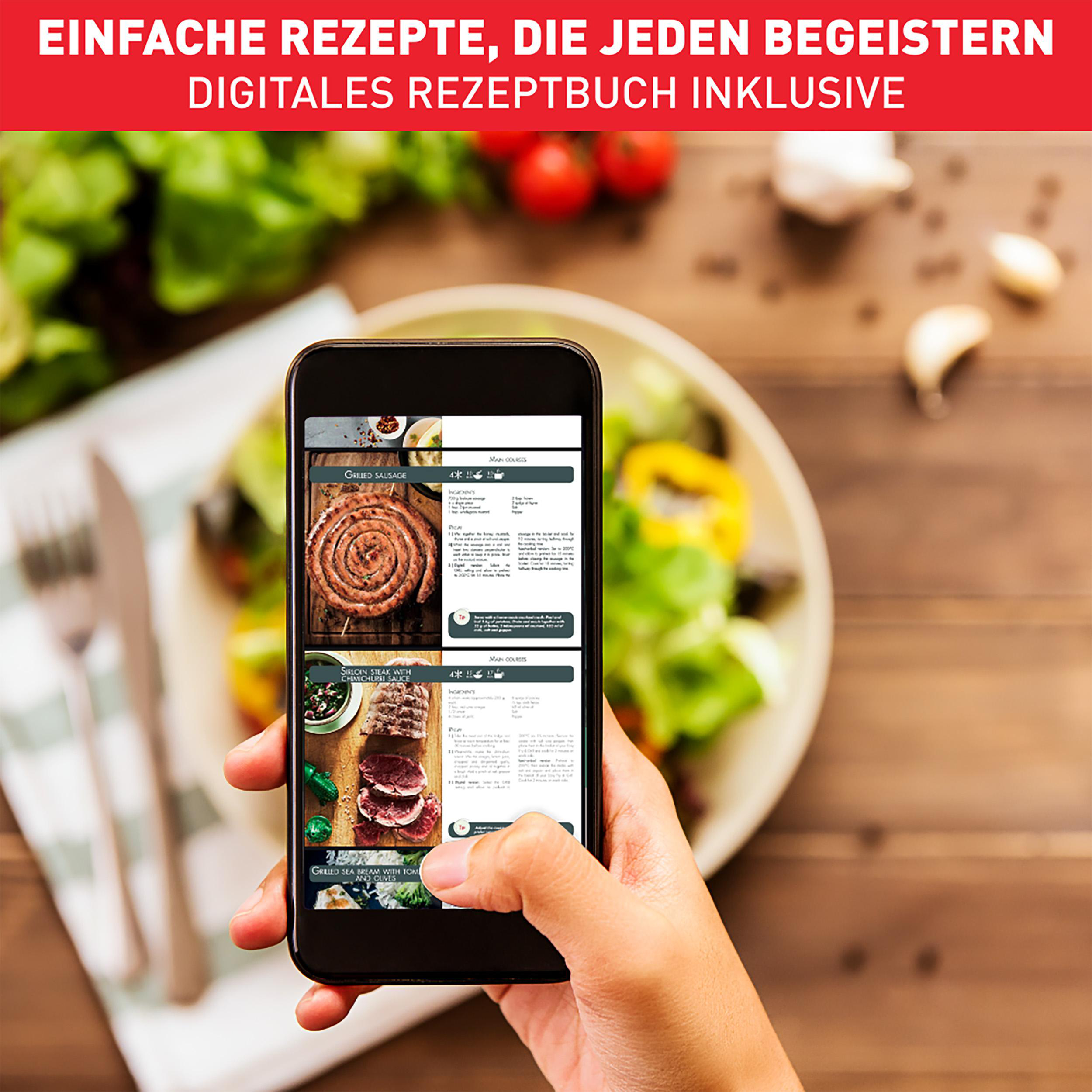 Ein Smartphone zeigt eine Rezept-App mit Essensbildern, gehalten von einer Hand über einem Holztisch.