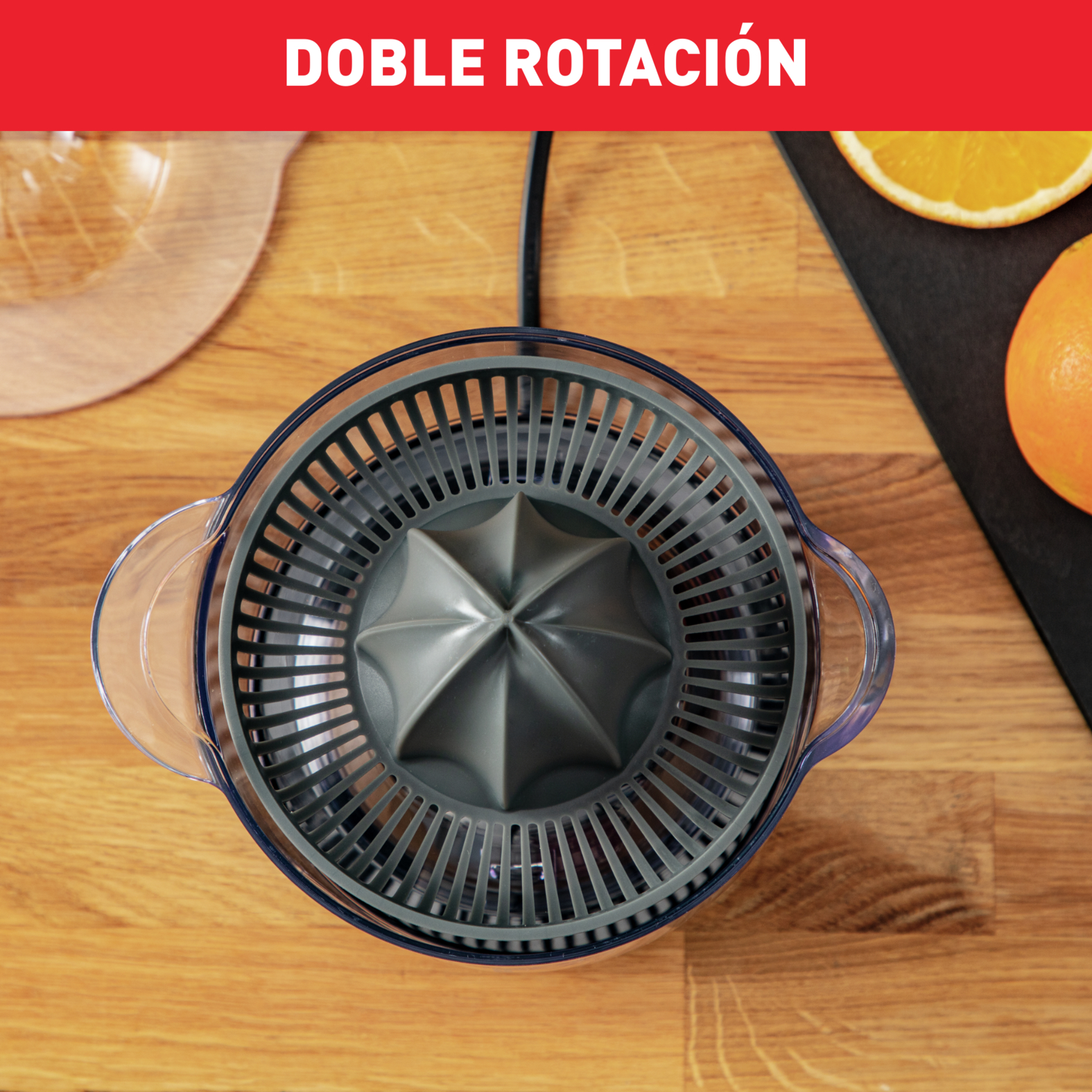 Una exprimidora de naranjas con tapa gris y recipiente transparente sobre una tabla de madera.
