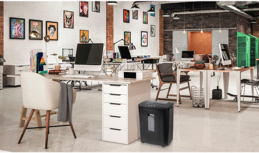 Scène de bureau avec bureaux, ordinateurs, art, une déchiqueteuse et une chaise.