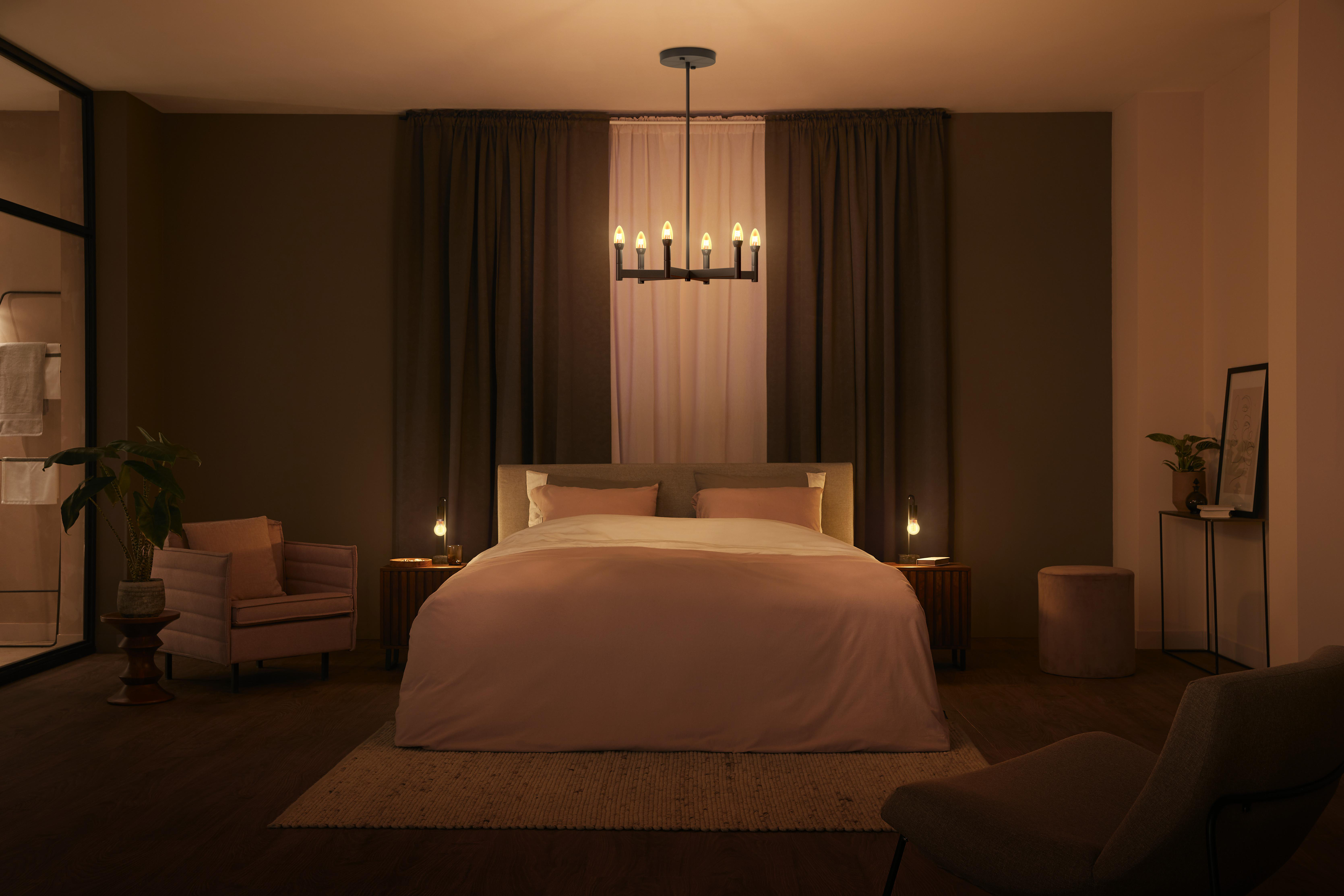 Schlafzimmer mit Bett, Lichtern und Vorhängen. Das Bett befindet sich in der Mitte.