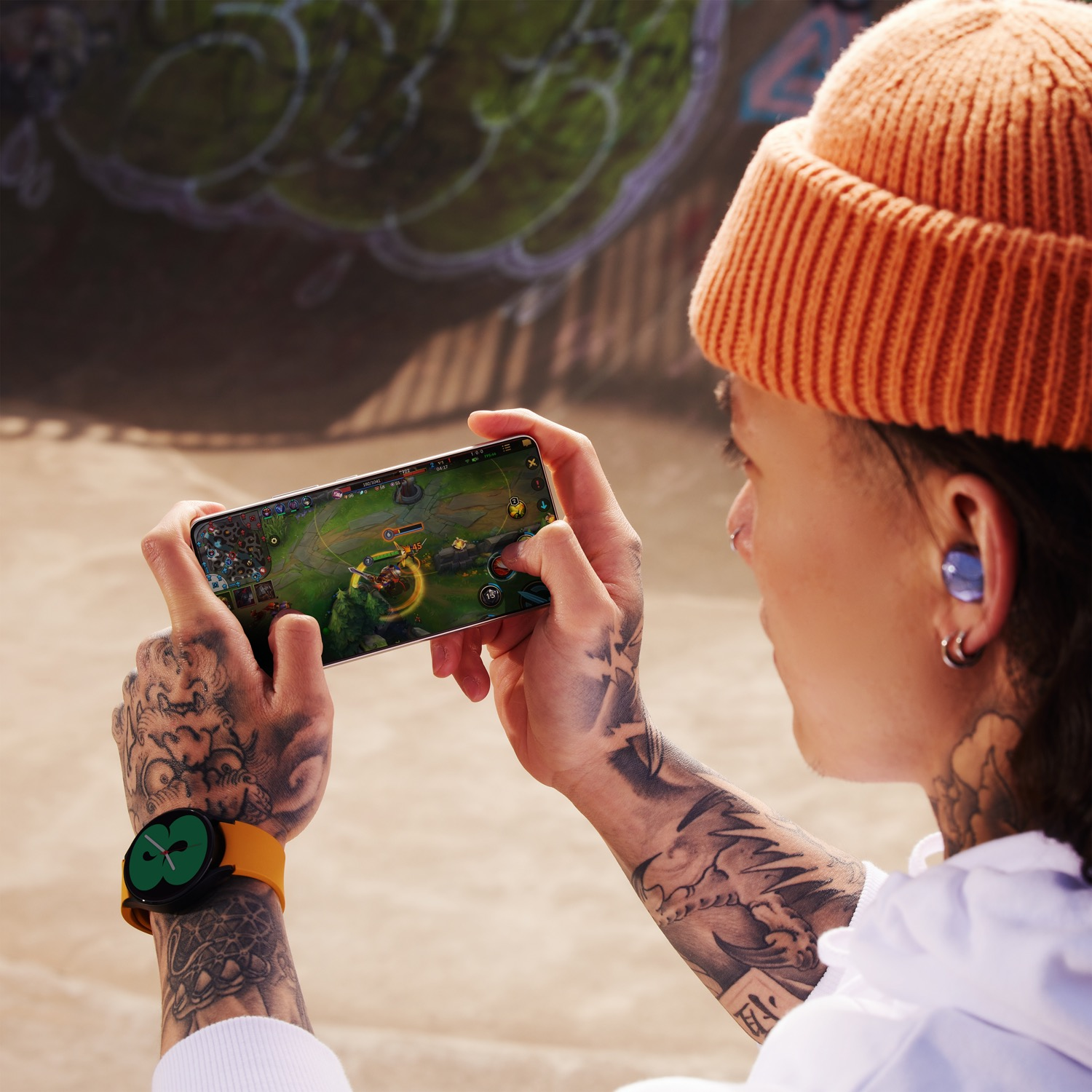 Persona jugando en un smartphone. Usa reloj y gorro.