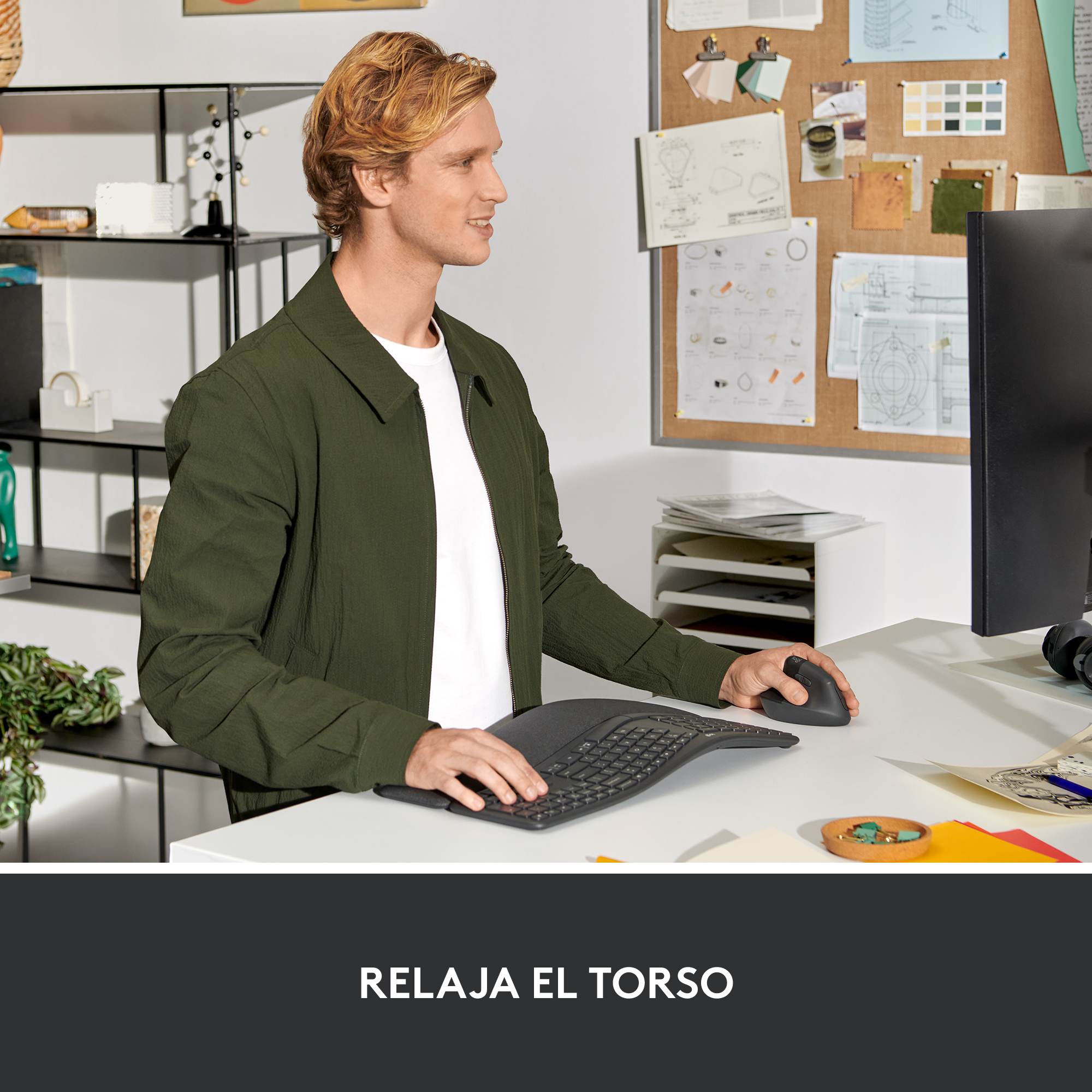 Hombre usando un teclado curvo y ratón en un escritorio, trabajando en una computadora. Sonriendo.