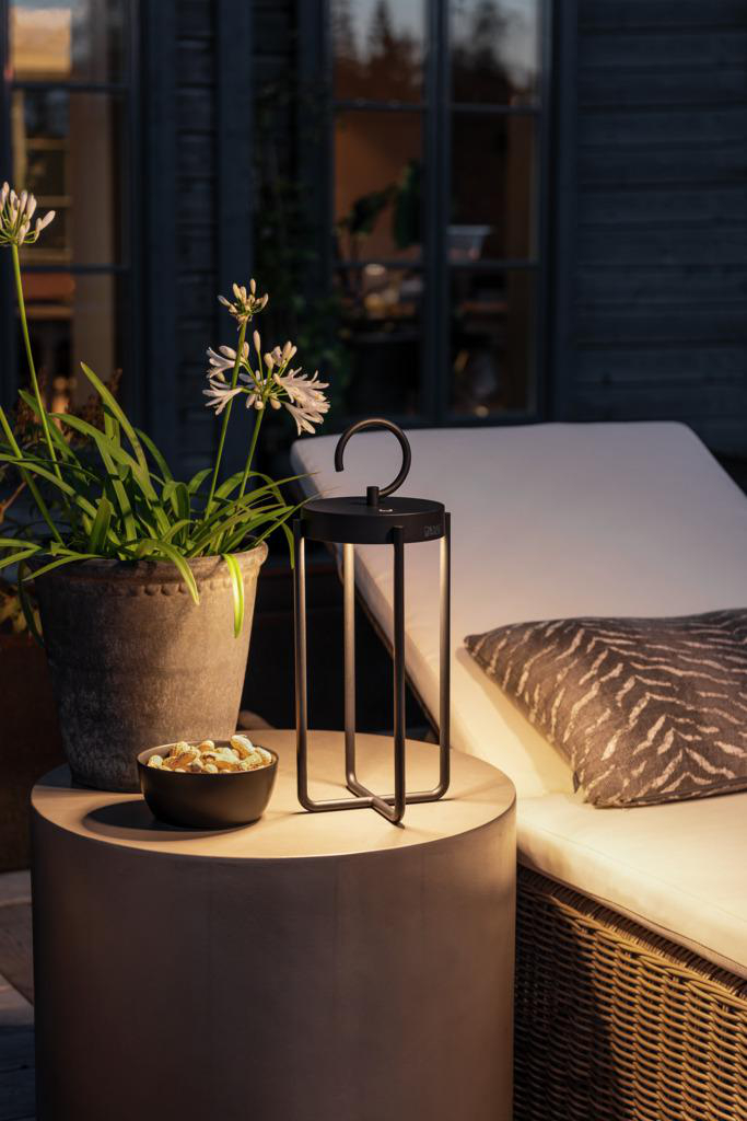 Szene im Freien, beleuchtete Laterne, Blumen und Snacks auf einem Tisch.