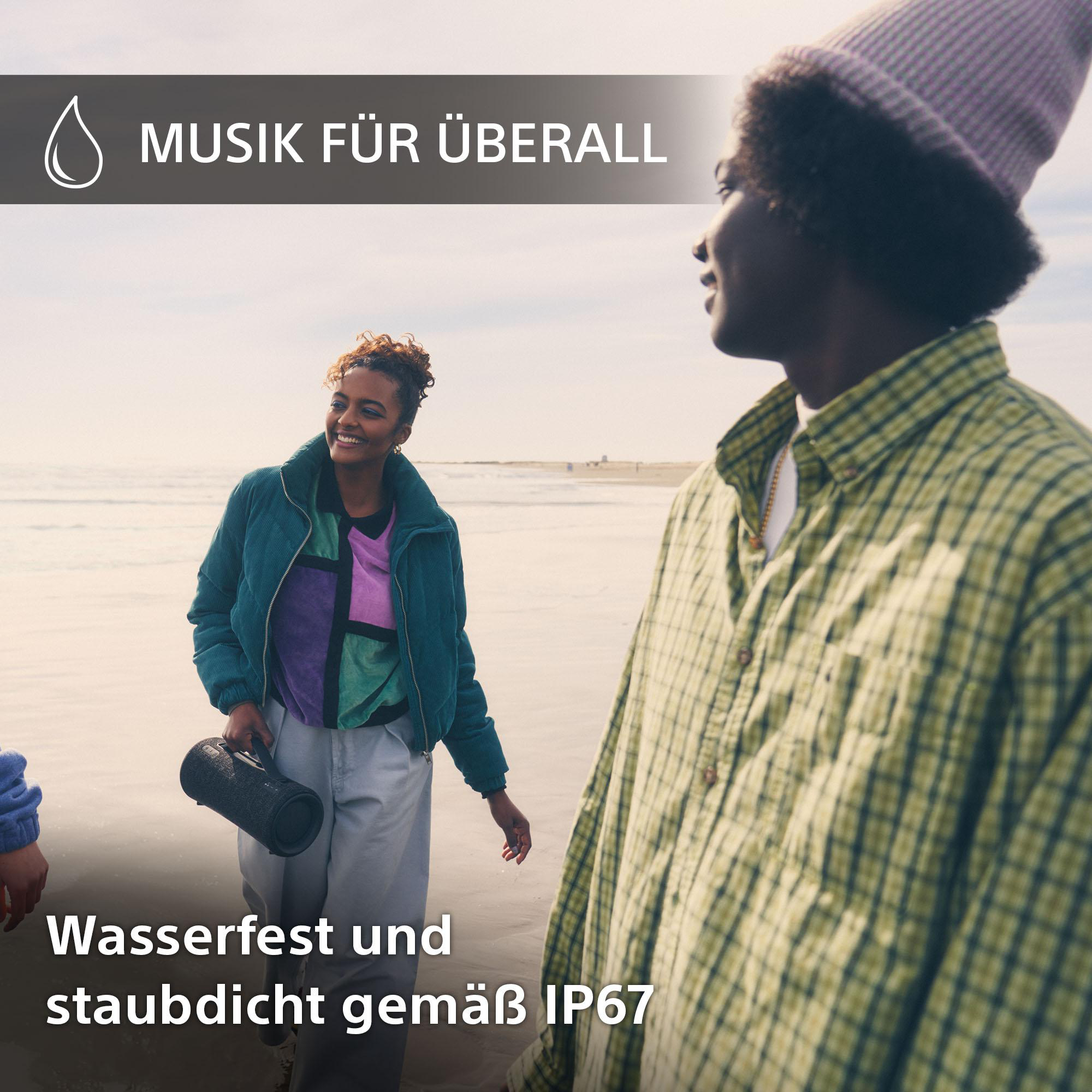 Zwei Personen am Strand, eine hält einen schwarzen Lautsprecher. Text: Musik überall. Wasserdicht IP67.