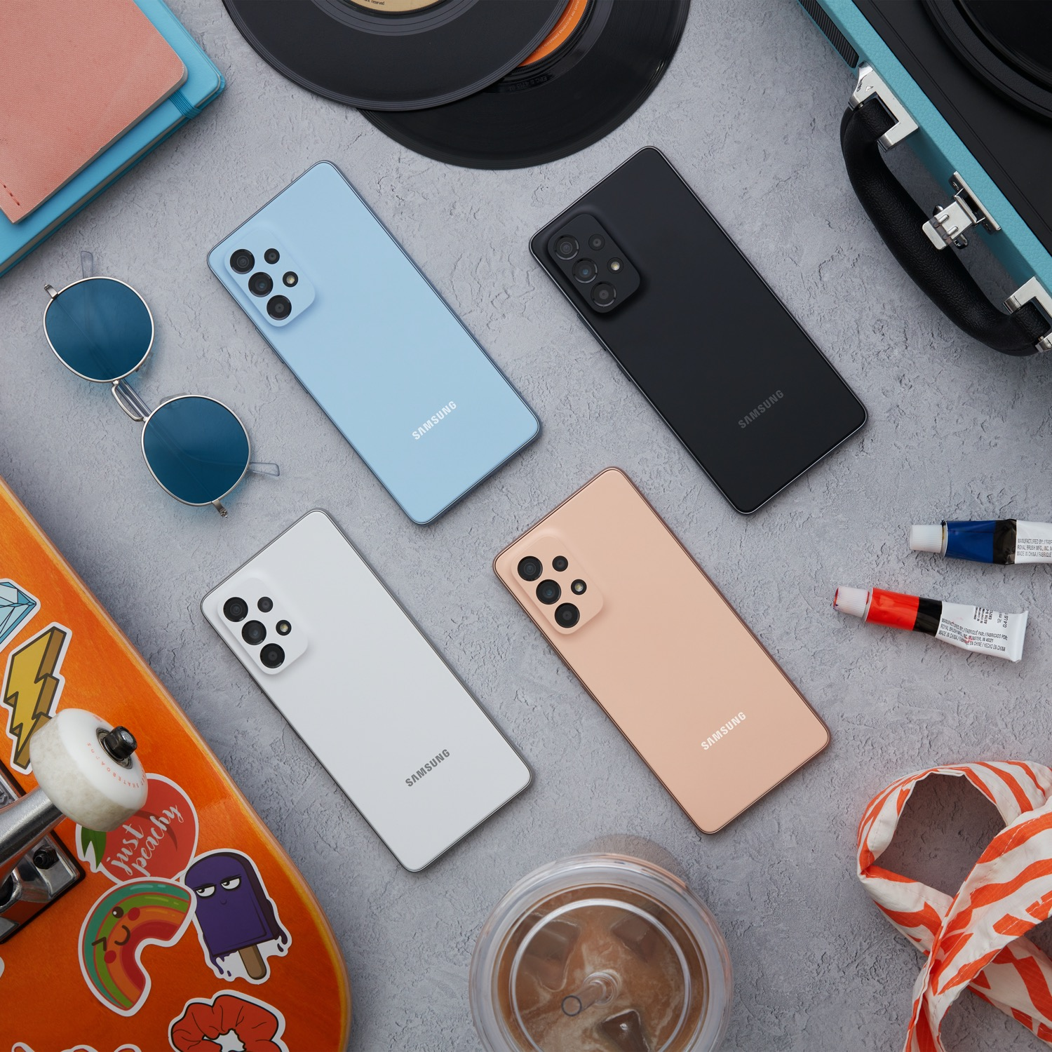 Cuatro teléfonos, gafas de sol, monopatín y útiles de arte sobre la mesa.