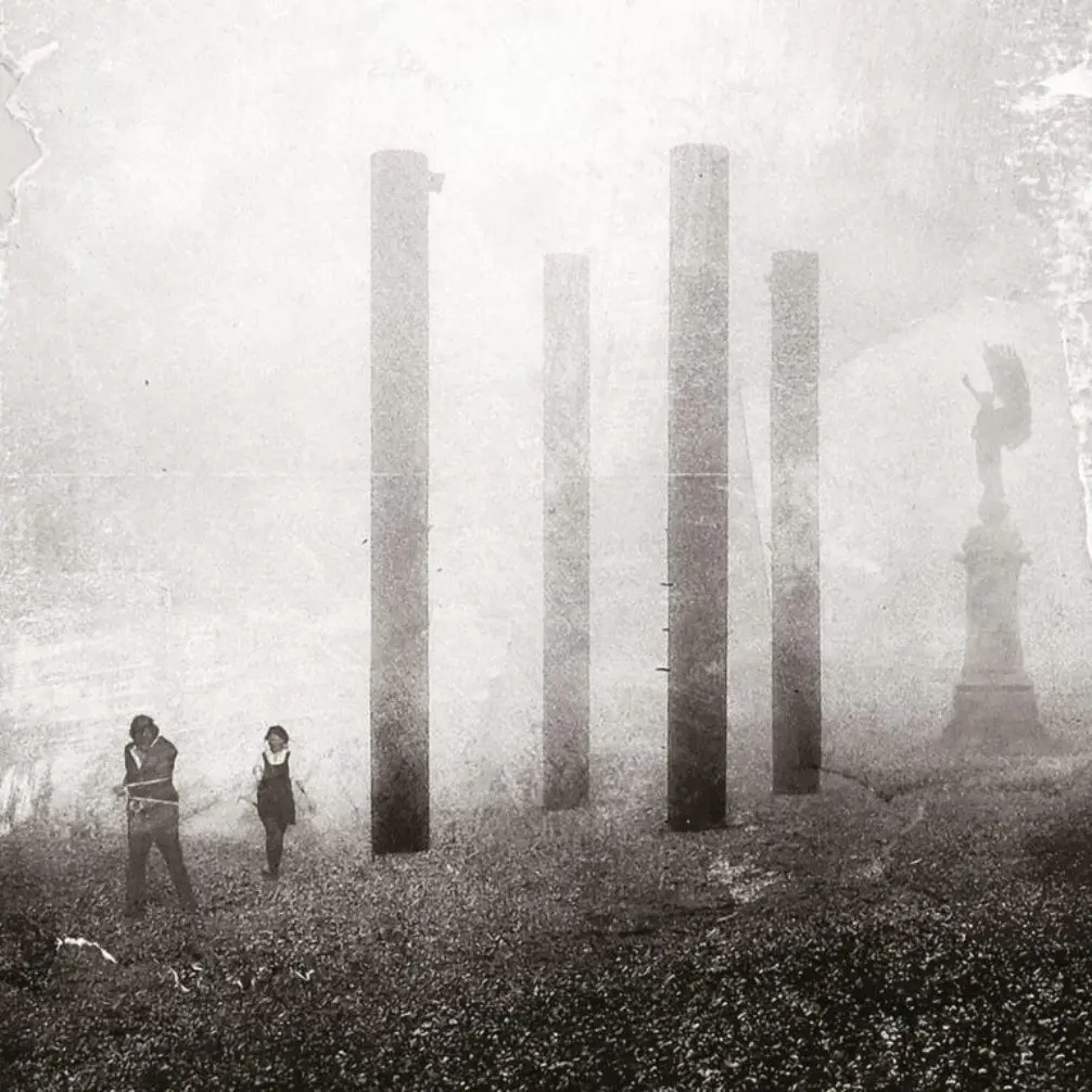 Photo monochrome avec des figures et des piliers dans un environnement brumeux.