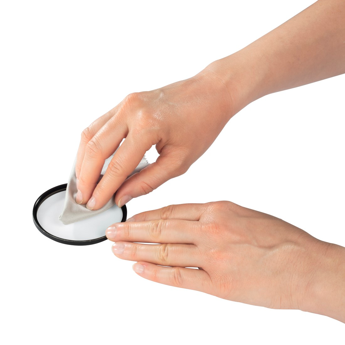Mains nettoyant un filtre de caméra avec un chiffon, fond blanc.