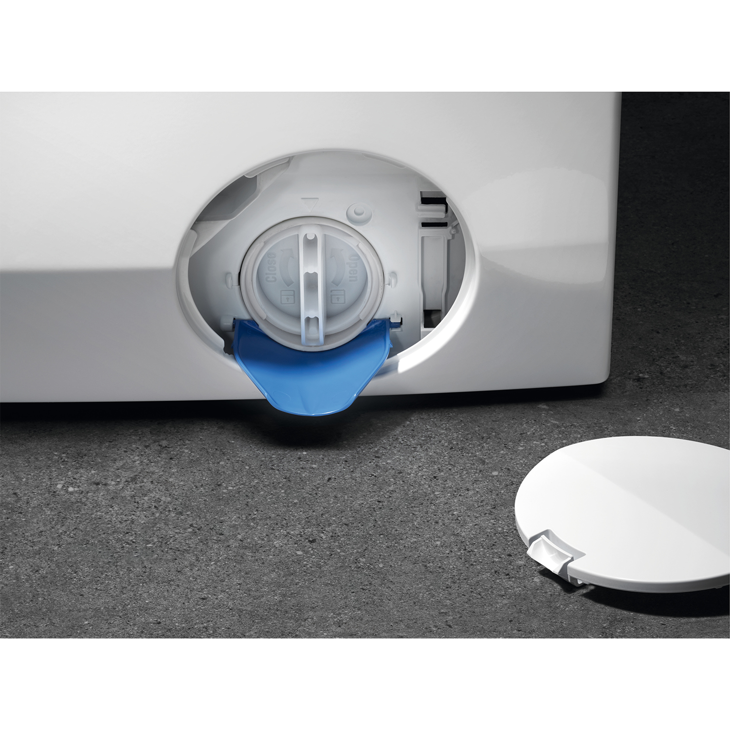 Primo piano dell'accesso al filtro di scarico di una lavatrice, con un coperchio blu estraibile visibile.
