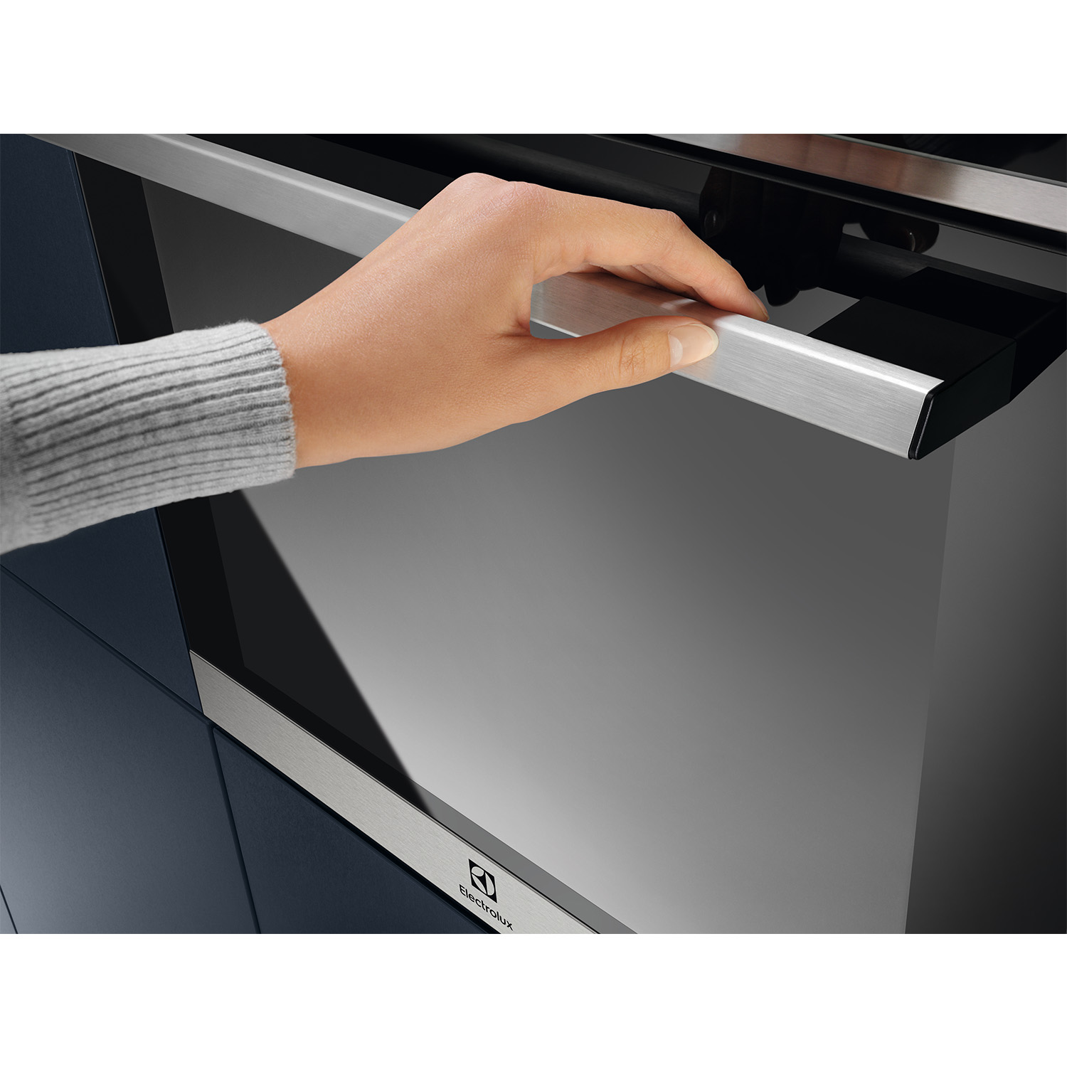 Mano che apre la maniglia della porta del forno, con logo Electrolux sulla porta.