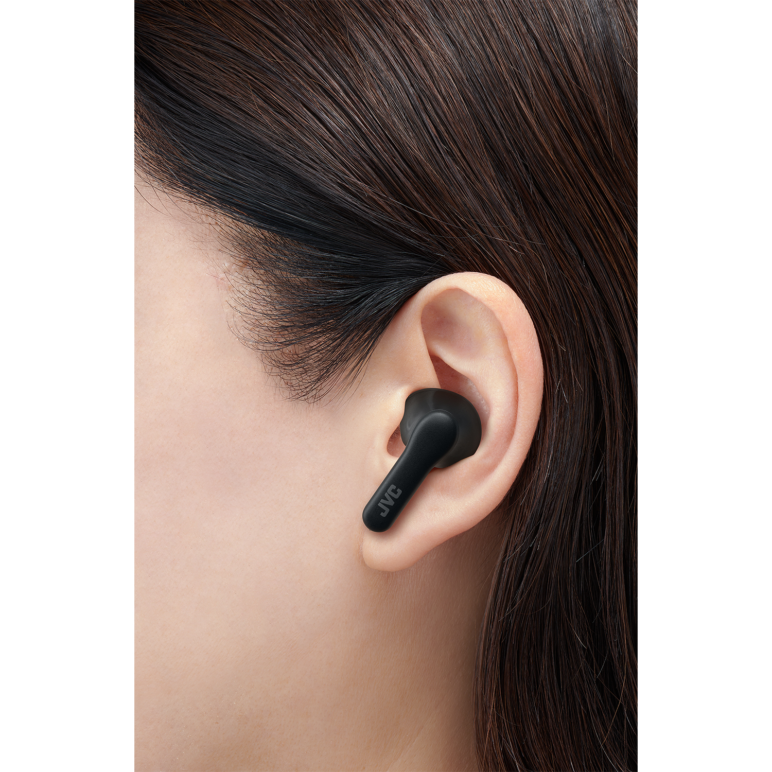 Primo piano di un auricolare JVC nero nell'orecchio di una donna, logo JVC visibile.